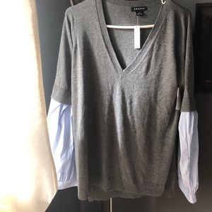 Gray sweater with blue and white bell sleeves.